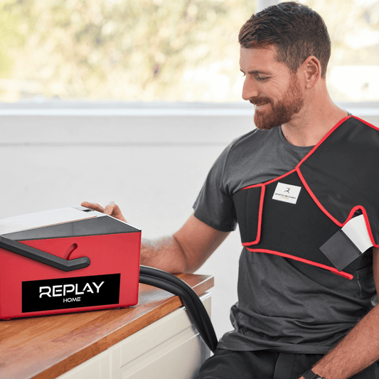Man using Replay Home ice compression unit with shoulder wrap for injury recovery at home