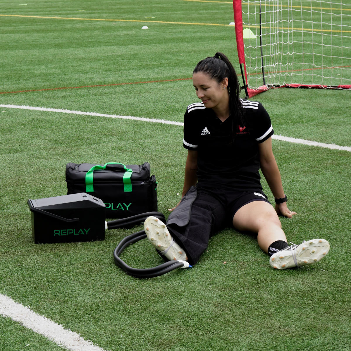 Athlete using Replay Pro ice compression leg wrap for recovery on soccer field