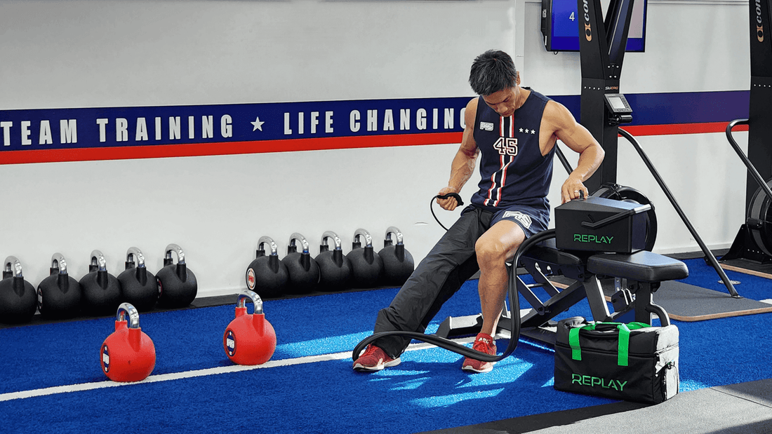 Athlete sitting in a gym using an ice compression recovery unit after training, showing the importance of rest and recovery for better performance.