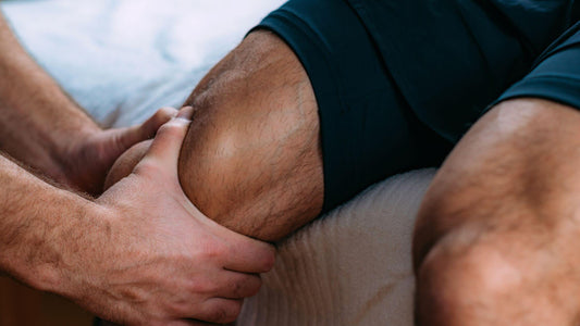 Hands supporting a swollen knee during a physical assessment, showing common signs of sport related inflammation.