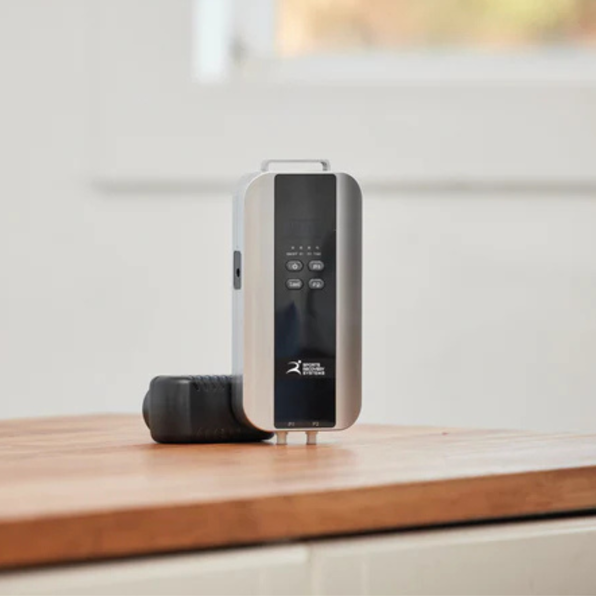 Replay Pro battery pack for portable ice compression recovery unit, displayed on wooden surface with blurred background