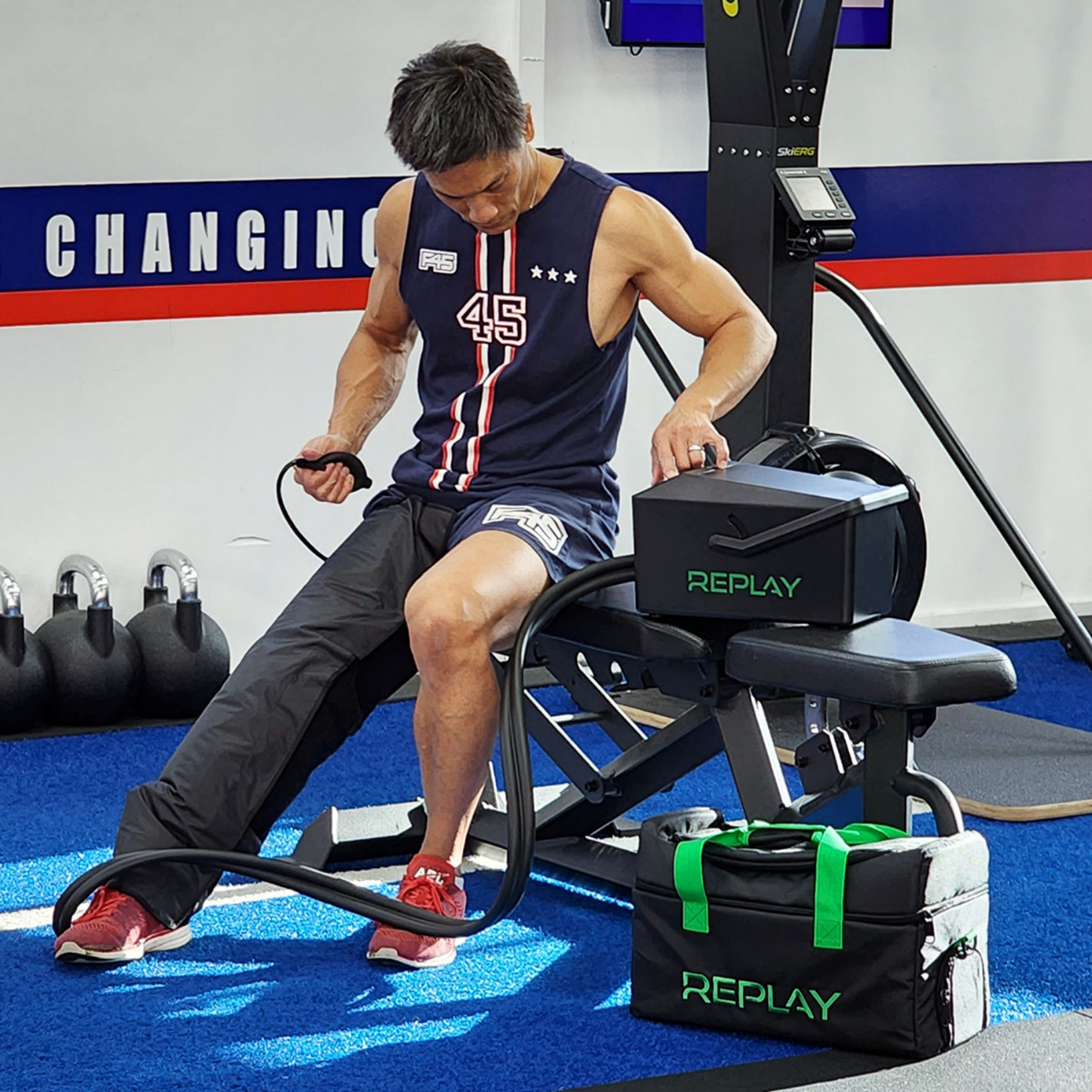Athlete using Replay Pro ice compression leg wrap for recovery in a gym session
