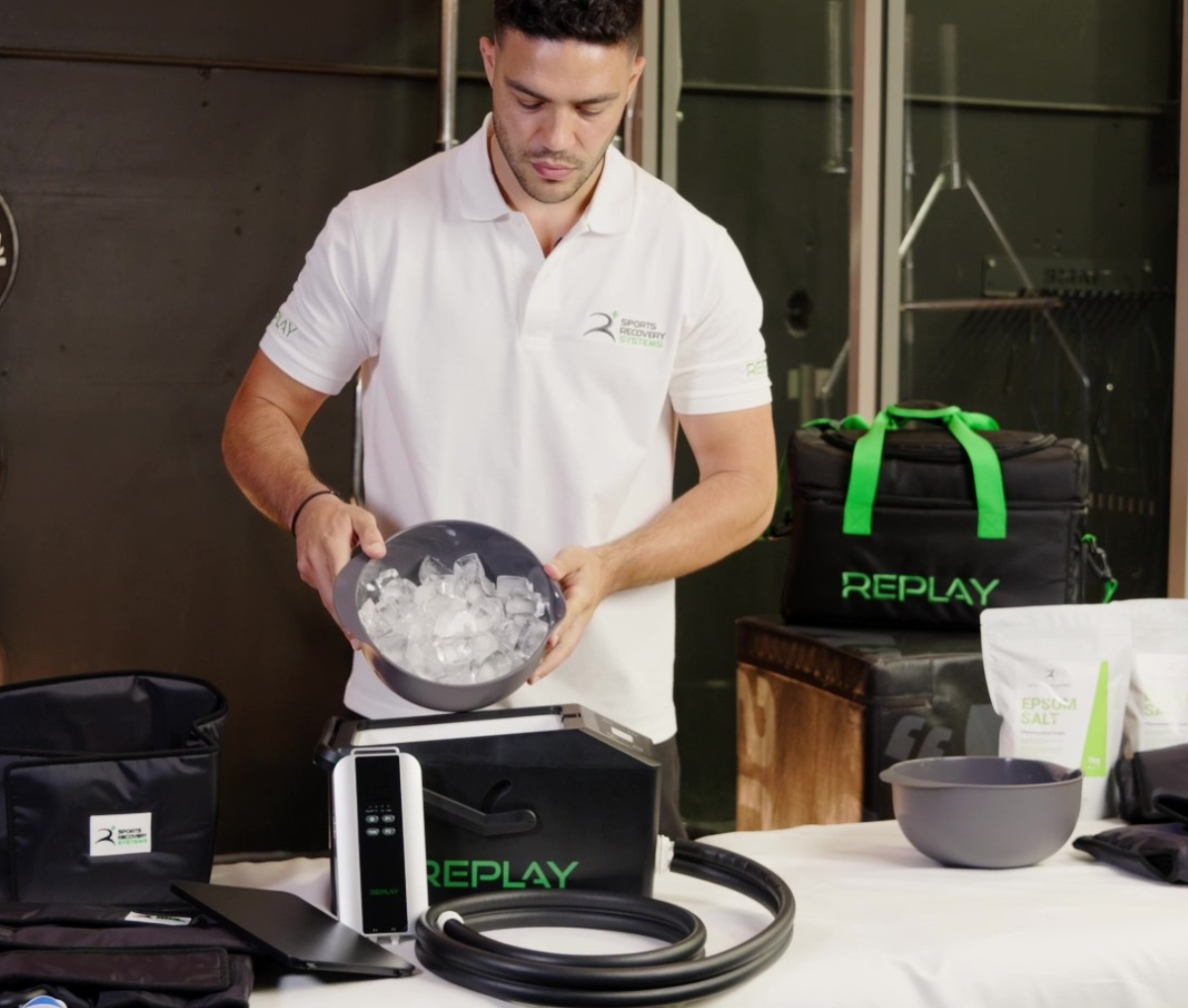 Replay Pro ice compression unit setup with athlete adding ice cubes, recovery equipment and carry bag on table
