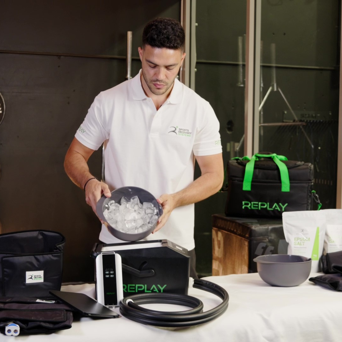 Physiotherapist preparing ice and demonstrating Replay Pro ice compression therapy unit with recovery accessories on table for muscle recovery setup